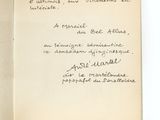 un livre ouvert, sur lequel est inscrit un poème manuscrit, posé sur une table