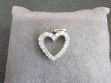 un gros plan d'une broche en diamant en forme de cœur posée sur un coussin