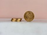 a gold coin sitting on top of a white table next to a stack of coins