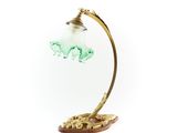 une image représentant une lampe avec un abat-jour en verre vert posé sur un socle en bois