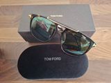 Lunettes de soleil Tom Ford avec leur boîte et leur étui, posées sur une table en bois