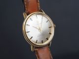 une image d'une montre-bracelet en or avec un bracelet en cuir marron