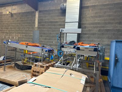 de nombreuses caisses sur des palettes dans un entrepôt équipé d'un tapis roulant