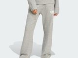 a woman in a grey sweatshirt and sweatpants stands in front of a white background