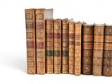 several old books are lined up in a row on a white surface