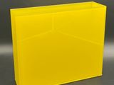 a yellow plastic box with a black lid on a gray background