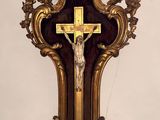 une croix accrochée au mur, sur laquelle est fixé un crucifix