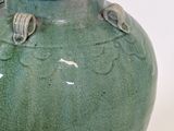 a large green vase with two birds on it