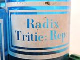a blue bottle with a label on it sitting next to a green bottle
