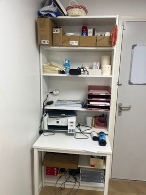 un bureau blanc sur lequel se trouve une imprimante, dans un coin de la pièce