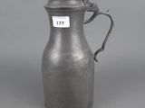 an old silver pitcher with a handle on a grey background