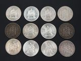 six different types of silver coins on a black surface