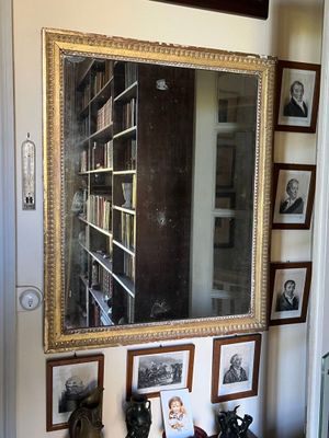 un miroir accroché au mur dans une pièce où sont accrochés des tableaux