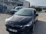 La voiture noire est garée sur le parking à côté de l'immeuble.