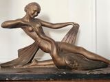 une statue en bronze représentant une femme allongée sur une table