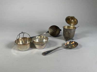 un assortiment d'ustensiles en argent, comprenant notamment des cuillères, des verres doseurs et des cuillères à mesurer