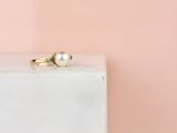 un gros plan d'une bague en perle posée sur un bloc blanc