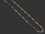 un collier en or composé d'une longue chaîne posée sur une surface noire