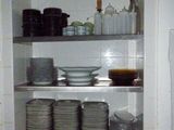 many plates and bowls on the shelves in the kitchen