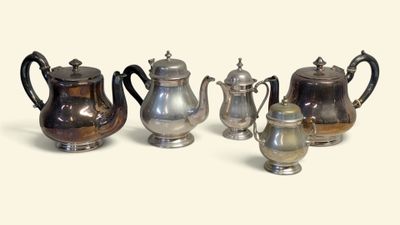cinq théières en argent et une cafetière posées sur une table