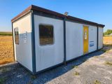 un petit bâtiment avec une porte jaune au milieu d'un champ