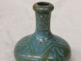 a small green vase sitting on a white surface