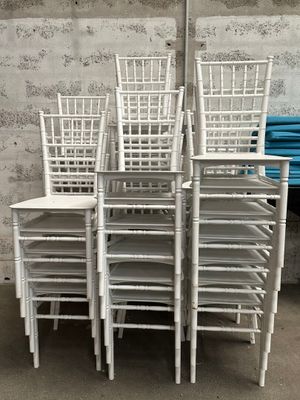Plusieurs chaises blanches sont empilées les unes sur les autres devant un mur.