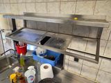 un évier en acier inoxydable dans une cuisine, avec une étagère au-dessus