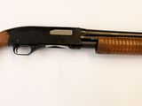 un vieux fusil posé sur une surface blanche, muni d'une crosse en bois