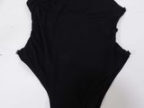 a black one piece swimsuit laying on top of a white table