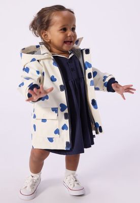 une petite fille en robe bleue et manteau blanc
