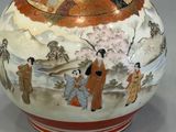 a vase with a painting on it sitting on a table