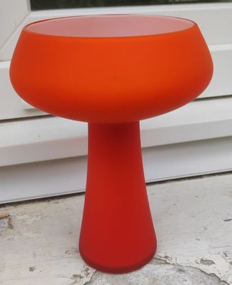 une table orange avec un piètement rouge, posée sur un rebord de fenêtre