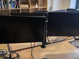 deux écrans d'ordinateur posés sur un bureau dans une pièce
