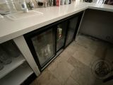 a white counter with a glass door and bottles on it