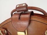 brown leather handbag with brass hardware on a white background