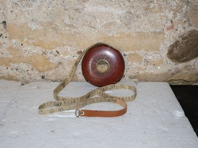 un mètre ruban enroulé autour d'un objet rouge posé sur une surface blanche