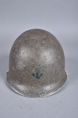 Un vieux casque repose sur une surface blanche, avec un fond gris.