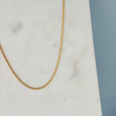un gros plan d'un collier à chaîne en or posé sur une surface en marbre