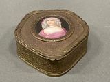 a gold box with a picture of a woman in a pink dress