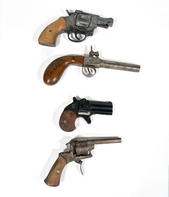trois vieux revolvers sont alignés sur une surface blanche