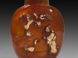 un vase en verre orange sur lequel est représenté un homme et une femme dans un paysage