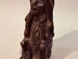 an old statue of a woman sitting on a rock on a white surface