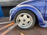 a blue car with a flat tire being towed by a tow truck