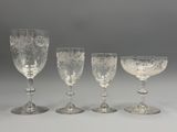 quatre verres à pied et un verre à vin posés sur une table