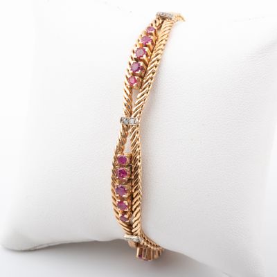 a close up of a gold bracelet with pink stones on it