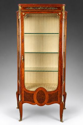 une vitrine ancienne avec des étagères en verre et des finitions dorées