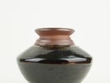 a black and brown vase sitting on a white surface