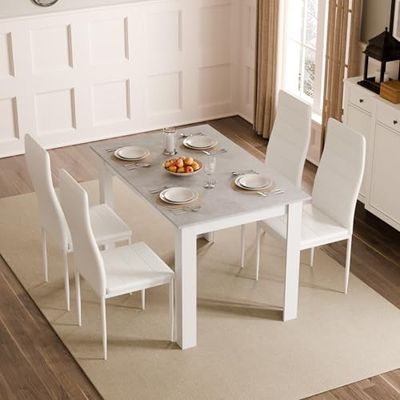 une table et des chaises blanches dans une pièce où est accrochée une horloge au mur