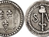 a close up of a silver coin with a cross on it